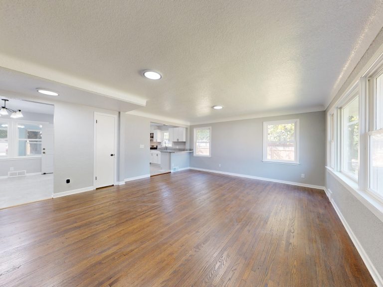 Warm oak hardwood flooring in an empty Utah room with tall windows