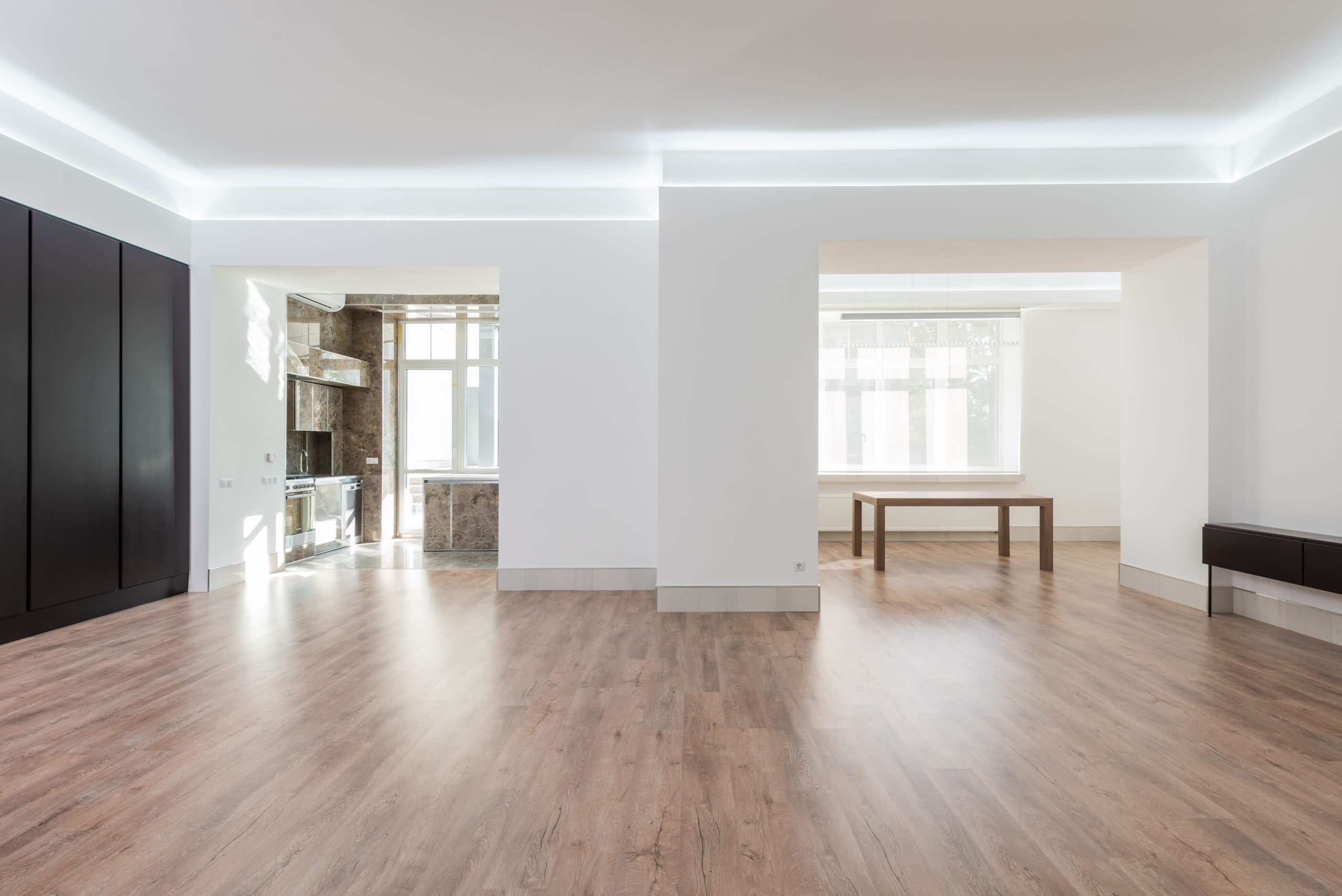 Light oak plank flooring running through an empty open-plan Utah living room and kitchen