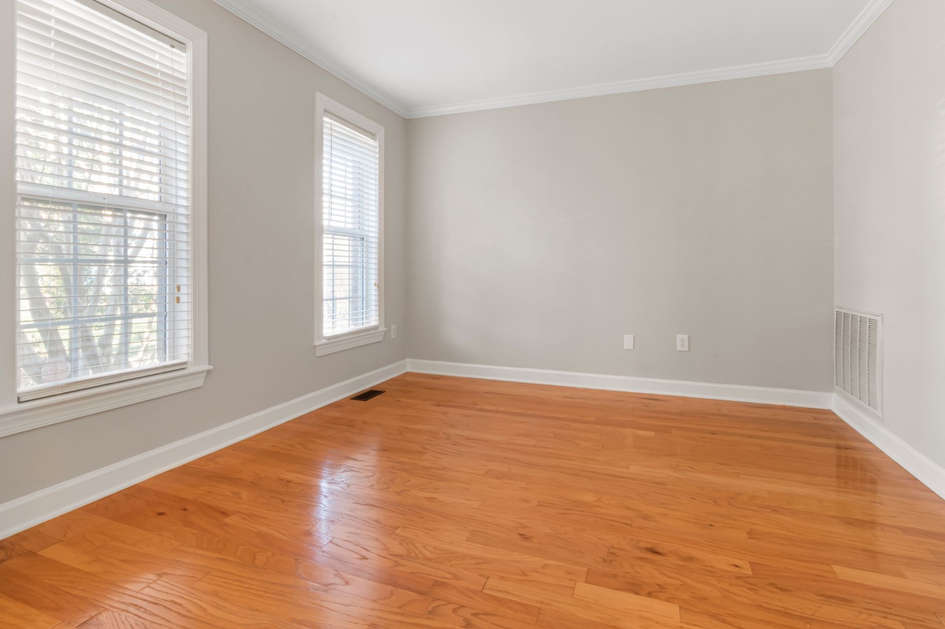 Spacious empty room with natural light, hardwood floors, and neutral walls