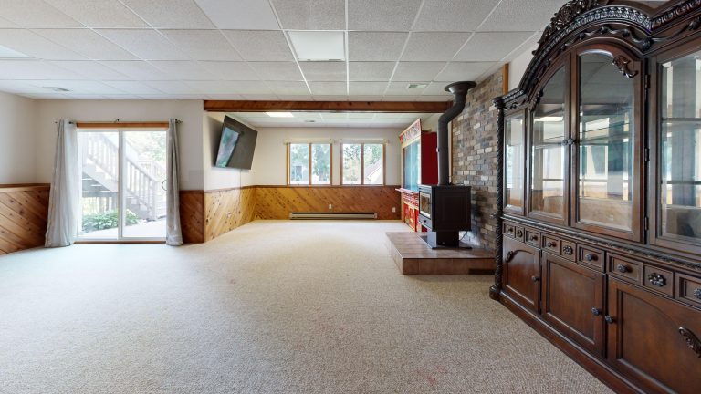 Carpet flooring in a large finished Utah basement with a stone fireplace
