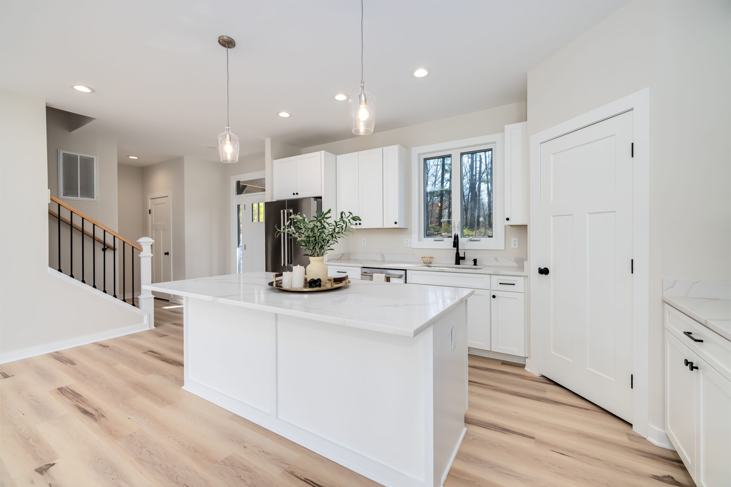 Light plank flooring in a white Utah kitchen with a central island