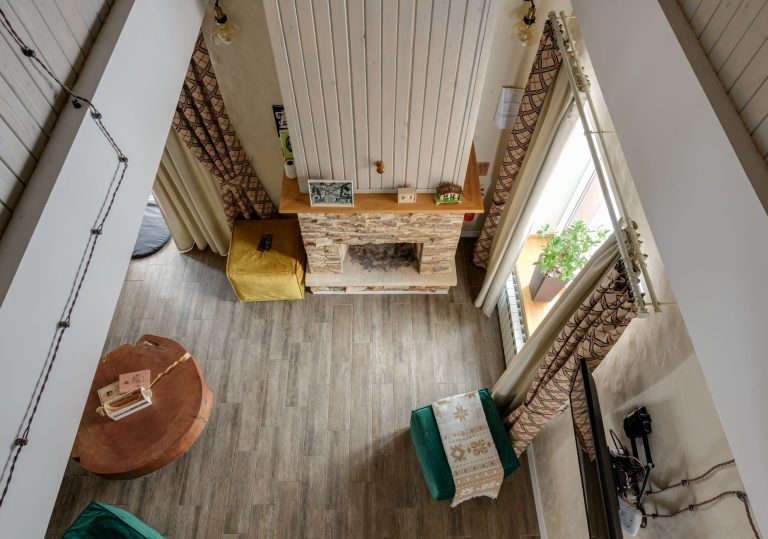 High-angle view of a stylish living room featuring a rustic fireplace and a wooden floor, showcasing modern interior design